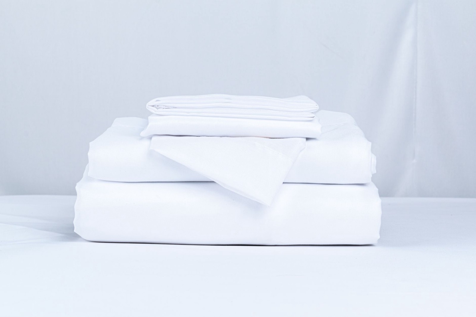Folded bedding layers showing the order that goes over a mattress and topper