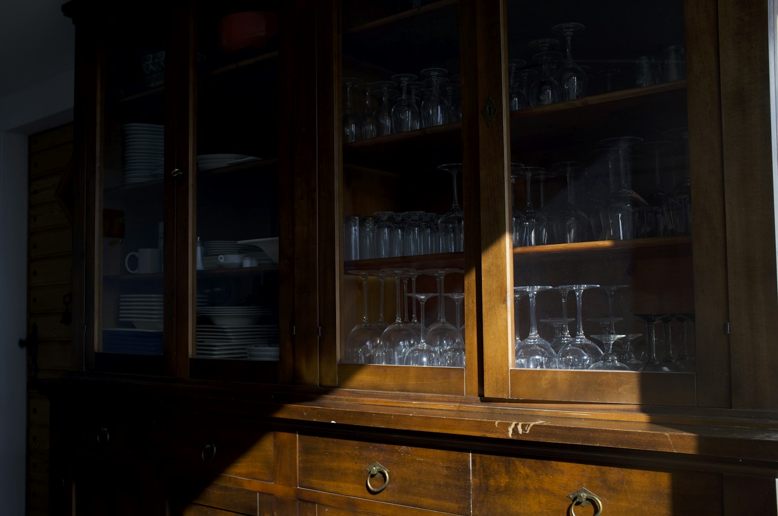 Glass-fronted cabinet displaying china and glassware on lit shelves