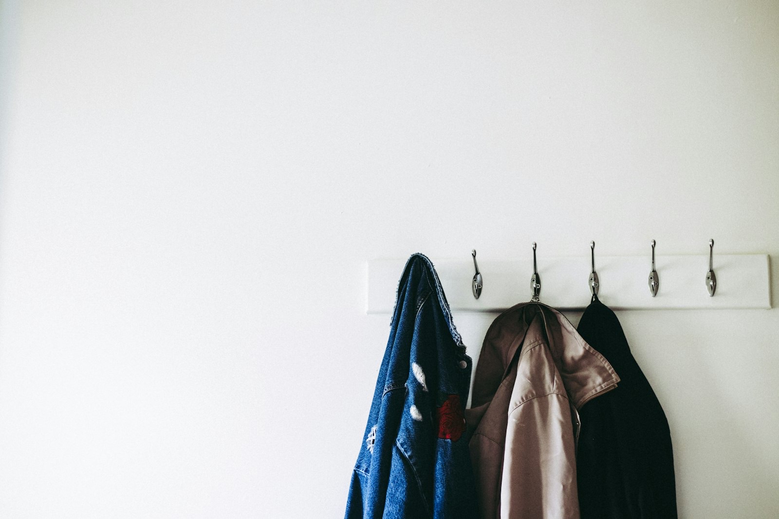Coats hanging on wall hooks at a height that clears the bench below