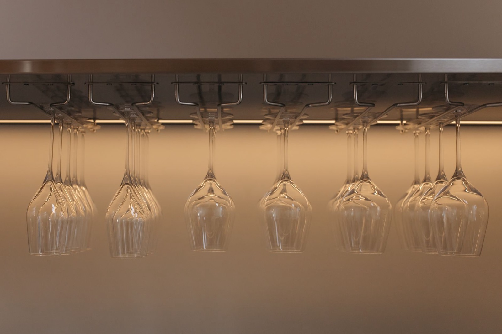Wine glasses stored inverted in a stemware rack above a bar surface